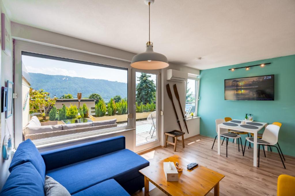 ein Wohnzimmer mit einem blauen Sofa und einem Tisch in der Unterkunft MOOKI Lake Apartment Ossiacher See&Gerlitzen in Sattendorf