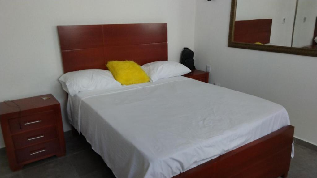 a bedroom with a bed with a yellow pillow on it at tropicana sur apt221 in Sosúa