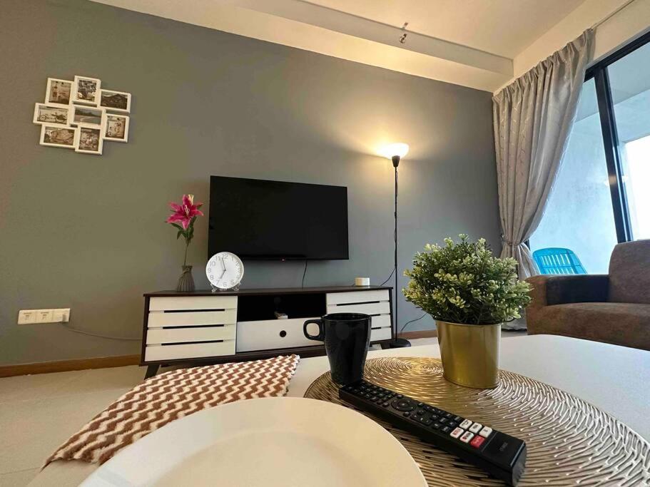 uma sala de estar com televisão e controlo remoto em LM HomeyB 3BR Coastline Family Suite for 4-14 Pax with Nexflix & Coway Water Purifier em Tanjong Tokong