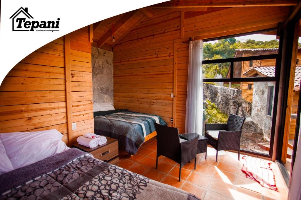 1 Schlafzimmer mit 2 Betten und einem großen Fenster in der Unterkunft Cabañas Tepani in Tzicuilán