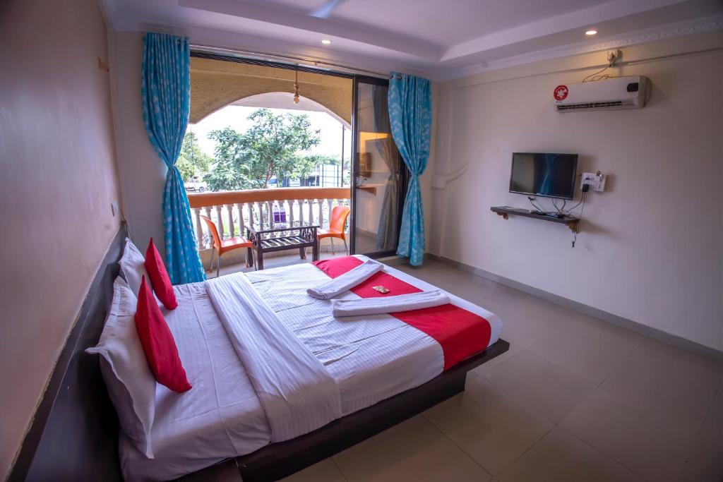 a bedroom with a bed and a balcony with a television at Hotel Om Palace in Lonavala