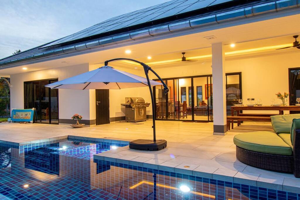 een zwembad met een parasol naast een huis bij RUSARDI Poolvilla Ao Nang - new Villa 4 Bedrooms 4 Bathrooms, 10m Pool in Ao Nang Beach