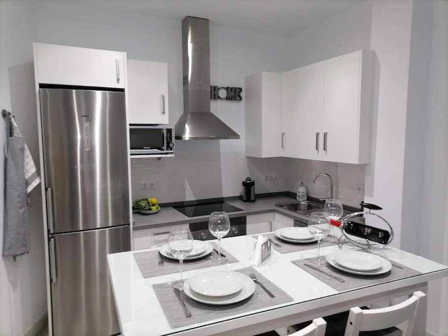 cocina con armarios blancos y nevera de acero inoxidable en Precioso apartamento con patio interior., en Medina Sidonia