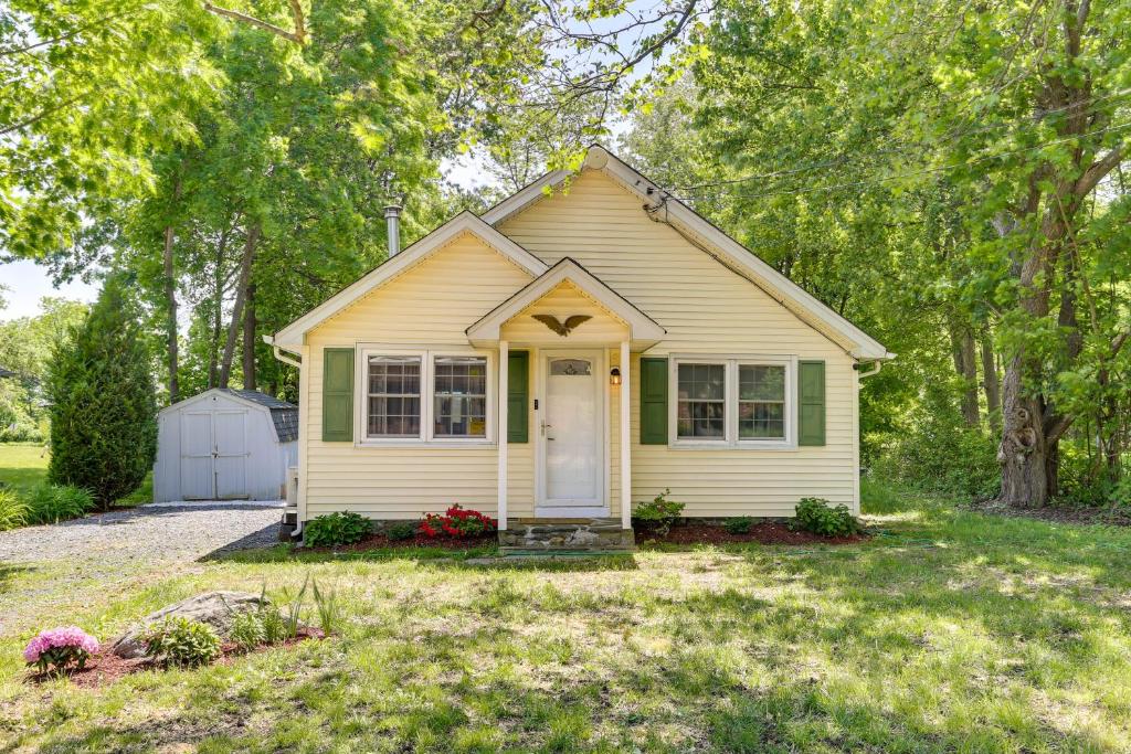 una pequeña casa amarilla con una puerta blanca en un patio en All-Season Vernon Township Lake House Retreat!, en Vernon Township