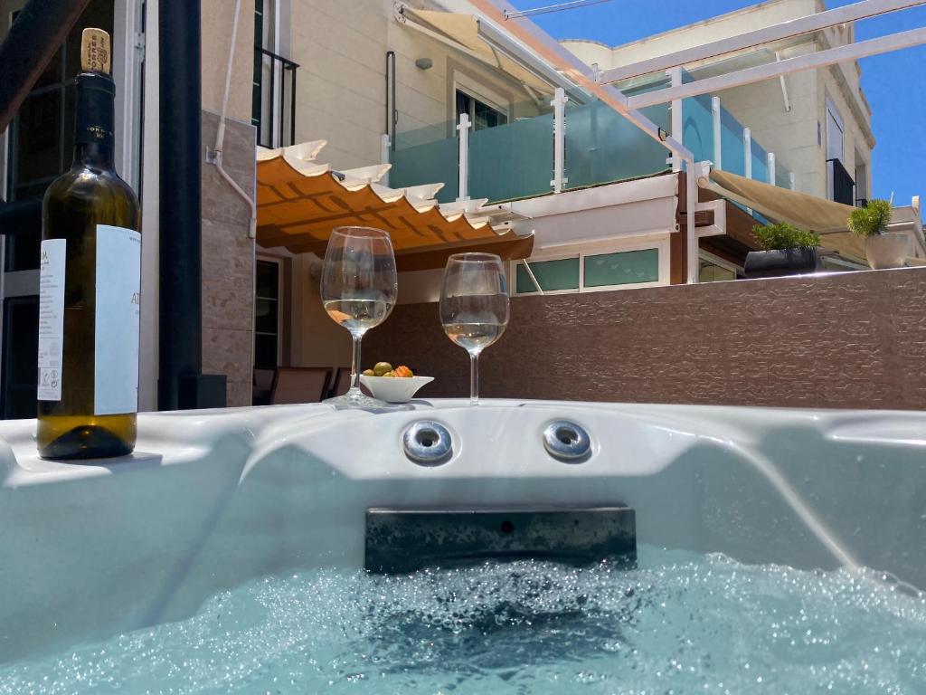 a hot tub with two glasses of wine in it at Spacious Apartment With Private Jacuzzi and Pool Access in Puerto Rico de Gran Canaria
