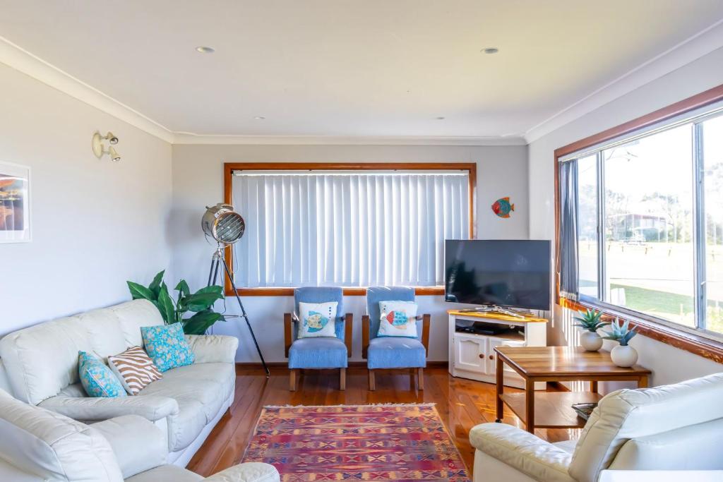 sala de estar con sofá blanco y sillas azules en Berrara Cove Beach House en Berrara
