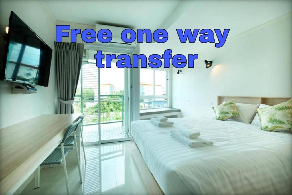 a room with a bed and a television with the words free one way transfer at beHOME Phuket in Nai Yang Beach