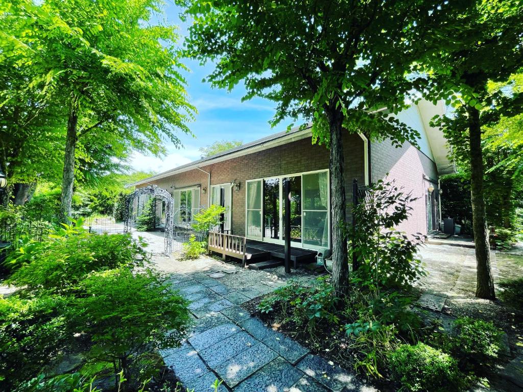 una casa con patio y árboles frente a ella en HOKUTO SATOYAMA BASE, en Hokuto