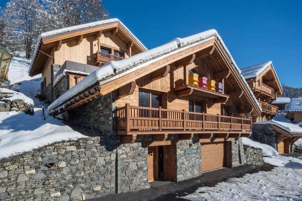 a log cabin with a deck in the snow at Chalet Kashmir 5MIN des pistes en voiture parking privé, spa, sauna in Les Allues