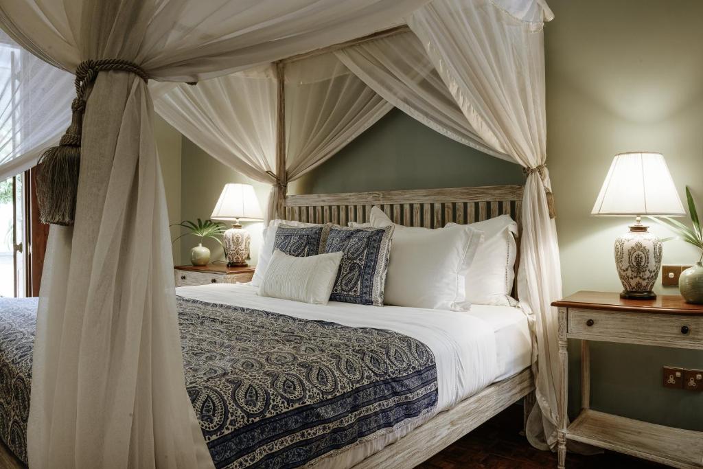 a bedroom with a canopy bed with white pillows at Maniumpathy Hotel in Colombo