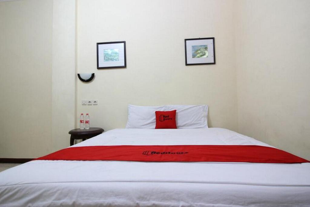 uma cama com um cobertor vermelho em cima em RedDoorz @ Mantrijeron 2 em Yogyakarta