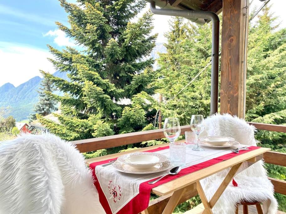 une table avec un tissu de table rouge et blanc sur une terrasse couverte dans l'établissement Alpine Majestic Escape - Balcone sulle Piste di Sci, à Champoluc