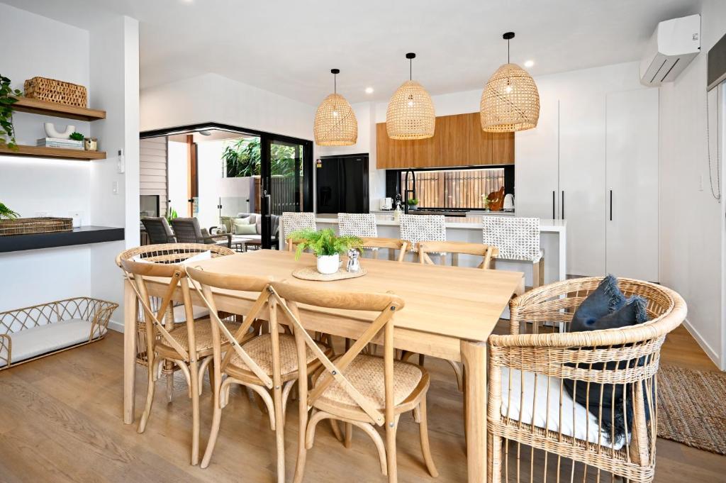 uma cozinha e sala de jantar com uma mesa de madeira e cadeiras em Stylish, Beachside 4 b/r Dream Home - 8 guests ZD7 em Kawana Waters