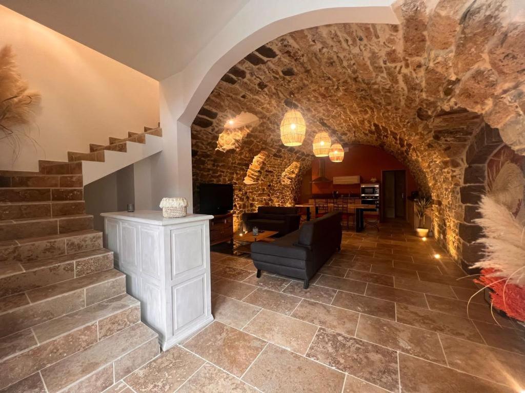salon ze schodami i kamienną ścianą w obiekcie Gite "La Coline d'Océane" - Neffies w mieście Néffiès