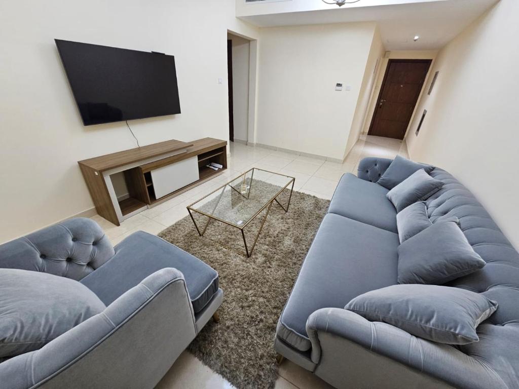 een woonkamer met twee blauwe banken en een televisie bij Modern & Cozy 1 Bedroom and 1 Living Room Apartment near Sharjah University in Sharjah