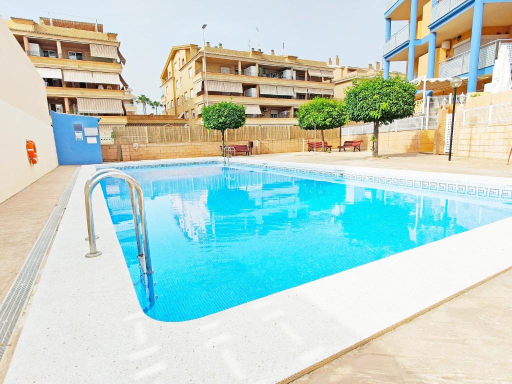 a swimming pool with blue water in a building at Global Properties, Apartamento con piscina y terraza en Canet playa in Canet de Berenguer