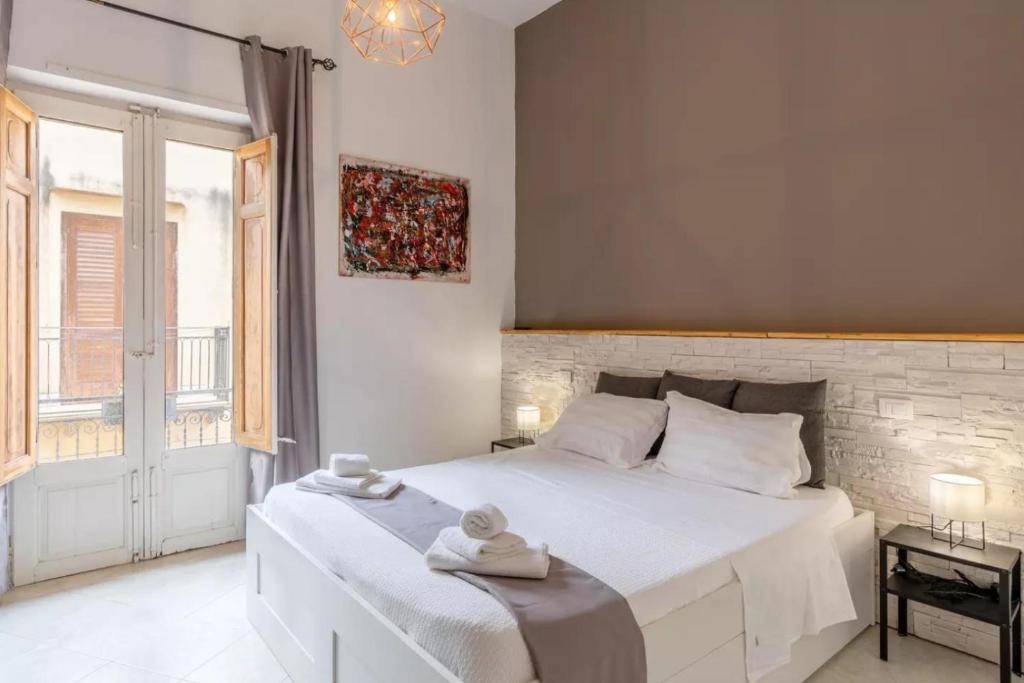 1 dormitorio con 1 cama blanca grande y toallas. en DOMUS, en Castellammare del Golfo