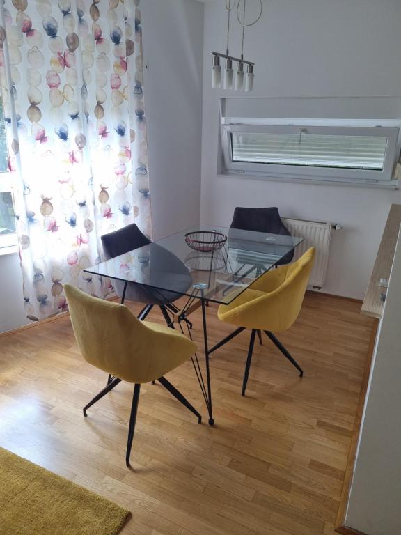 a dining room with a glass table and yellow chairs at Apartman Fran in Zagreb