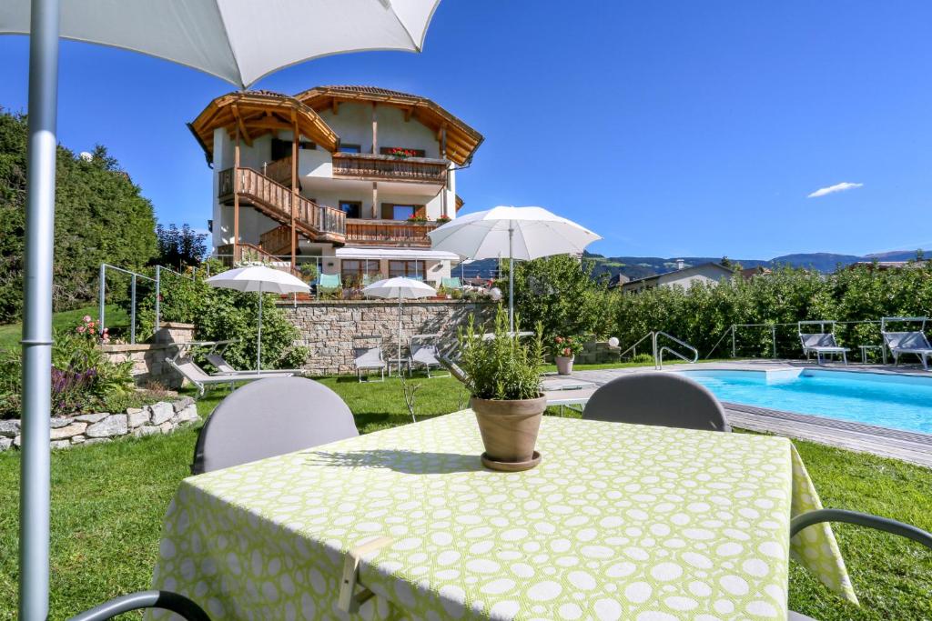 a table with an umbrella in front of a house at Hotel Ploseblick in Natz-Schabs