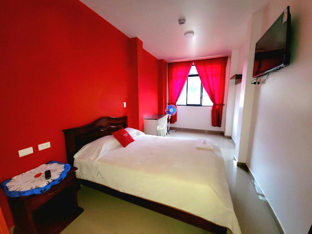 Dormitorio rojo con cama y ventana en Hostal Carolina, en Yantzaza