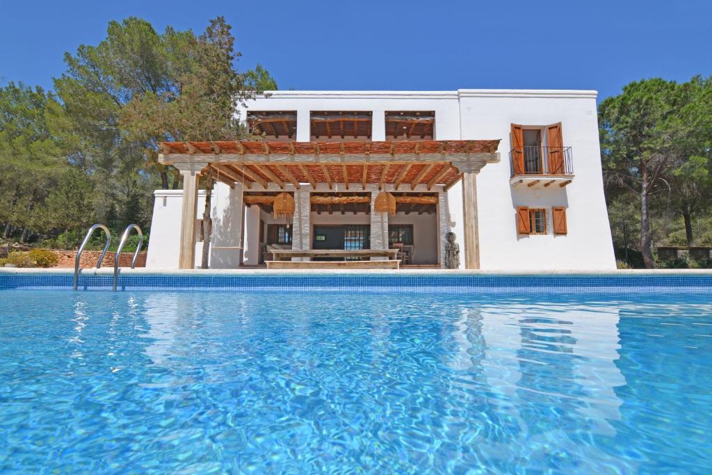 une villa avec une piscine en face d'une maison dans l'établissement Can Rich, à Santa Gertrudis de Fruitera