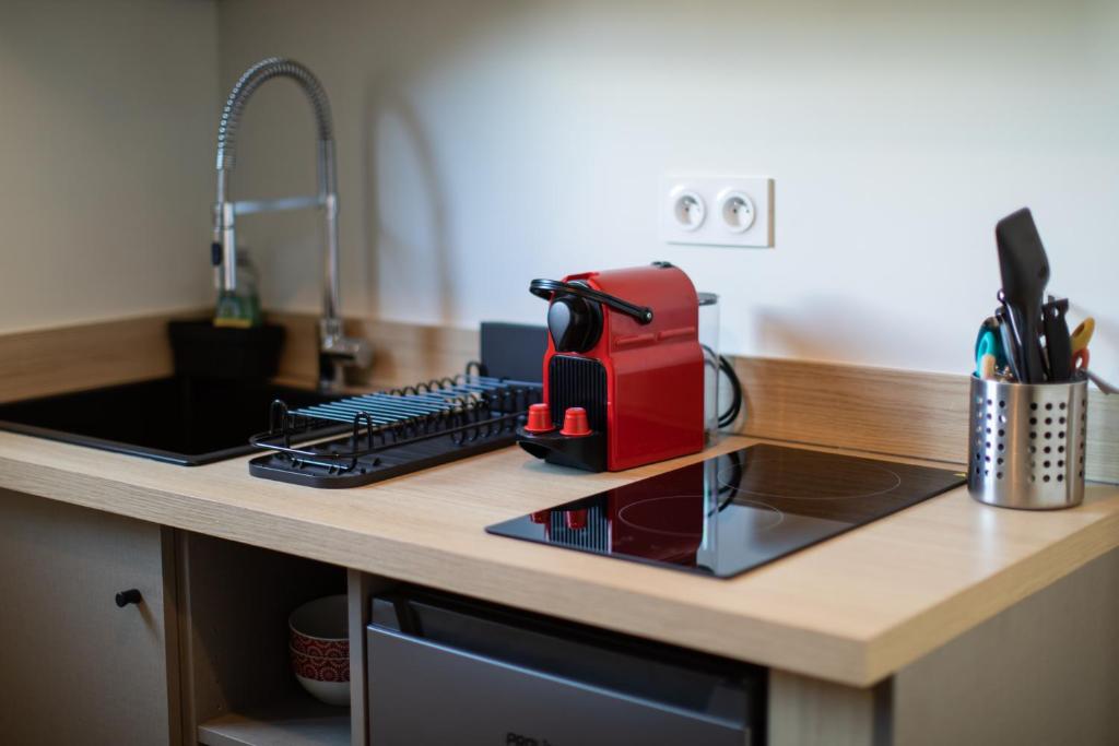 a kitchen counter with a red toaster sitting on a stove at Hôtel de la Baie in Crozon