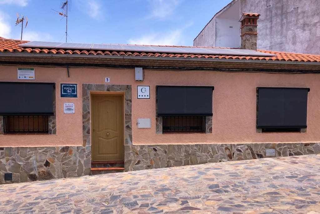 a building with a brown door and two windows at Casa Rural La Posada del 42 in Carrascalejo