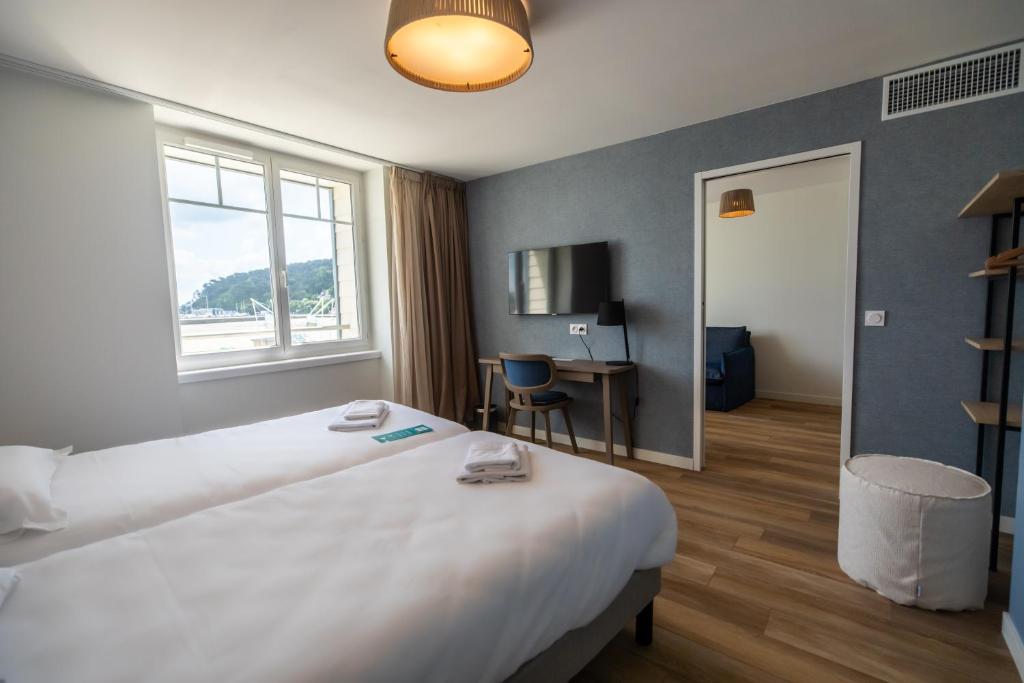 a hotel room with a large bed and a desk at Hôtel de la Baie in Crozon