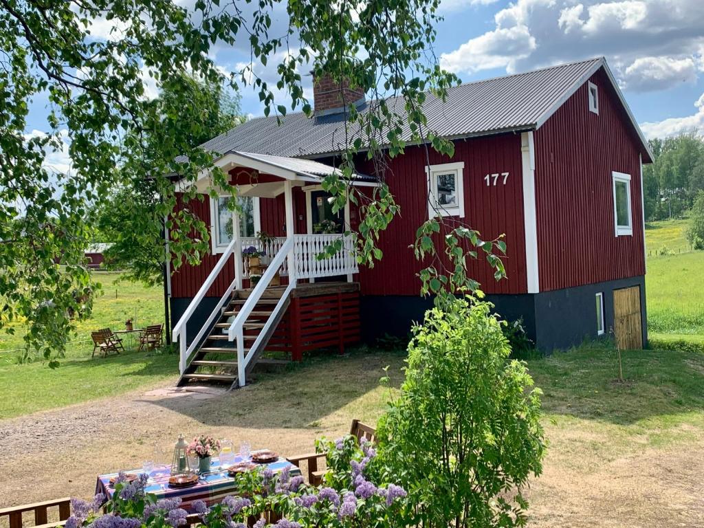un granero rojo con una mesa delante en Super cosy cottage in heart of Dalarna, en Västra Fors