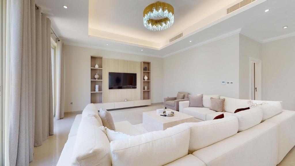 a living room with a white couch and a tv at Primestay - Flame Tree Ridge 4BR Villa with Private Pool in Dubai