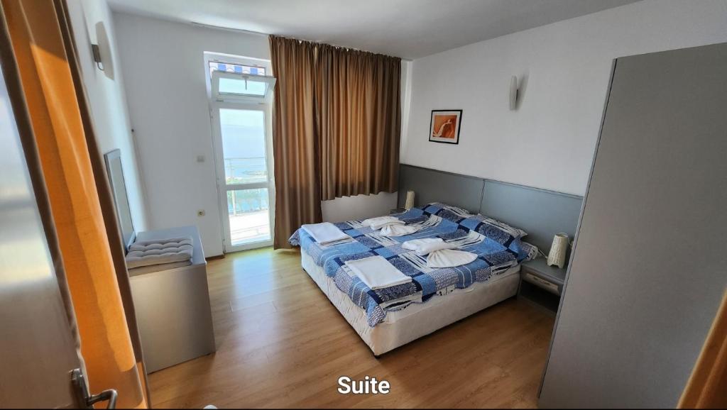 a bedroom with a bed with a blue comforter and a window at Nushev Hotel in Sveti Vlas