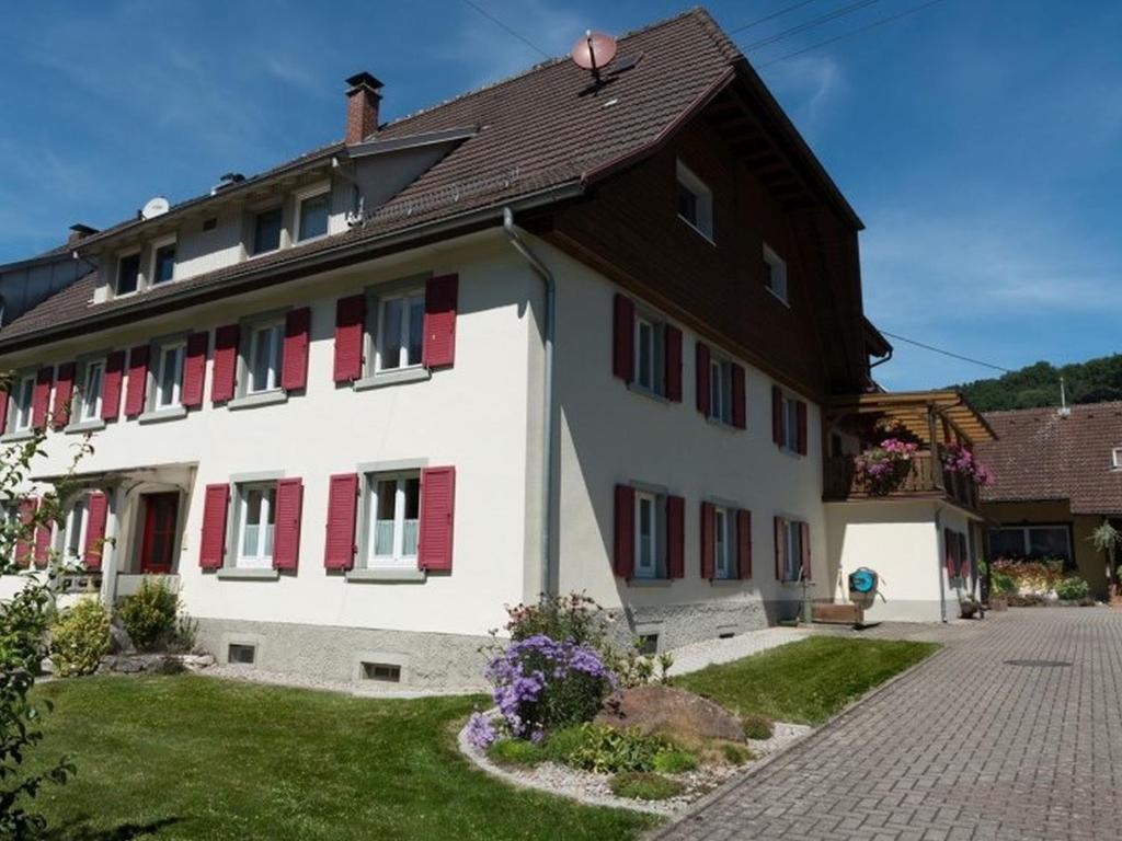 un grande edificio bianco con finestre con persiane rosse di Haus Belchenwind a Münstertal/Schwarzwald
