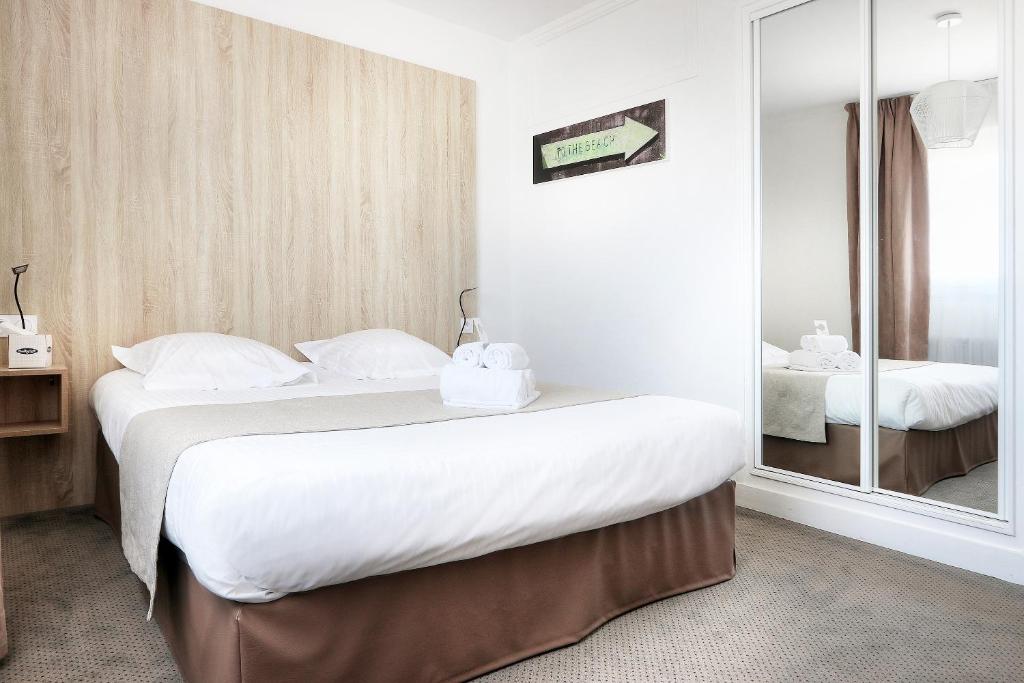 a hotel room with two beds and a mirror at Hôtel La Petite Sirène Quiberon in Quiberon