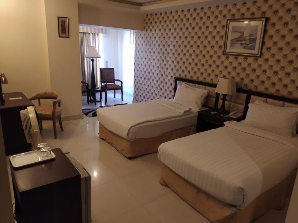 Habitación de hotel con 2 camas y escritorio en Royal Desert Palm Hotel, en Rahimyar Khan