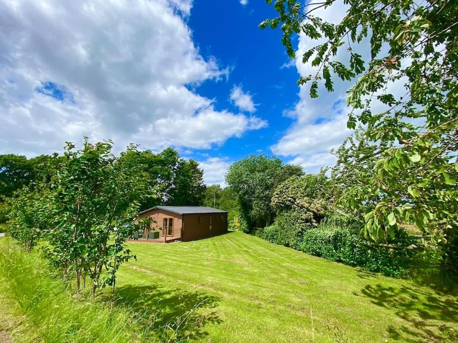 a house in the middle of a grassy field at Gorstage Meadows Luxury 2 Bedroom Lodge in Rural Cheshire in Hartford