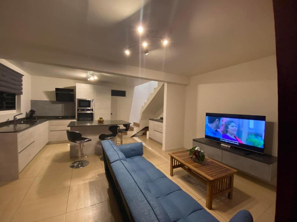 un soggiorno con divano blu e TV di Beach side Duplex a Punaauia