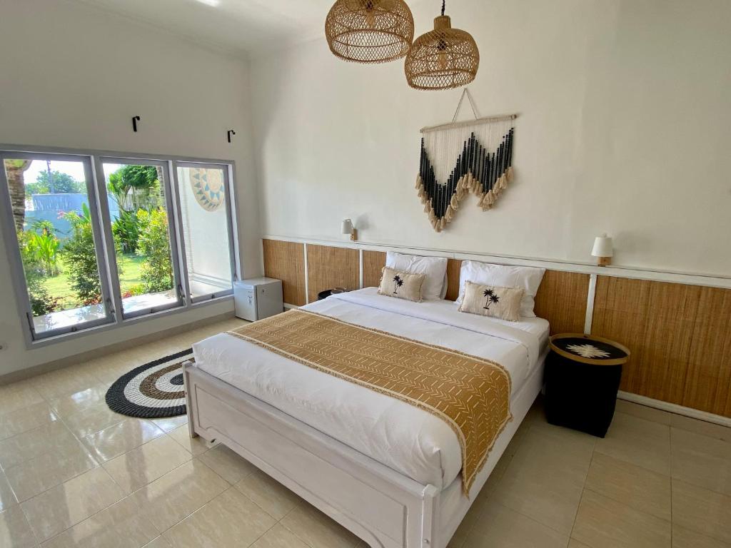 a bedroom with a large white bed and two windows at Bella Bali in Uluwatu