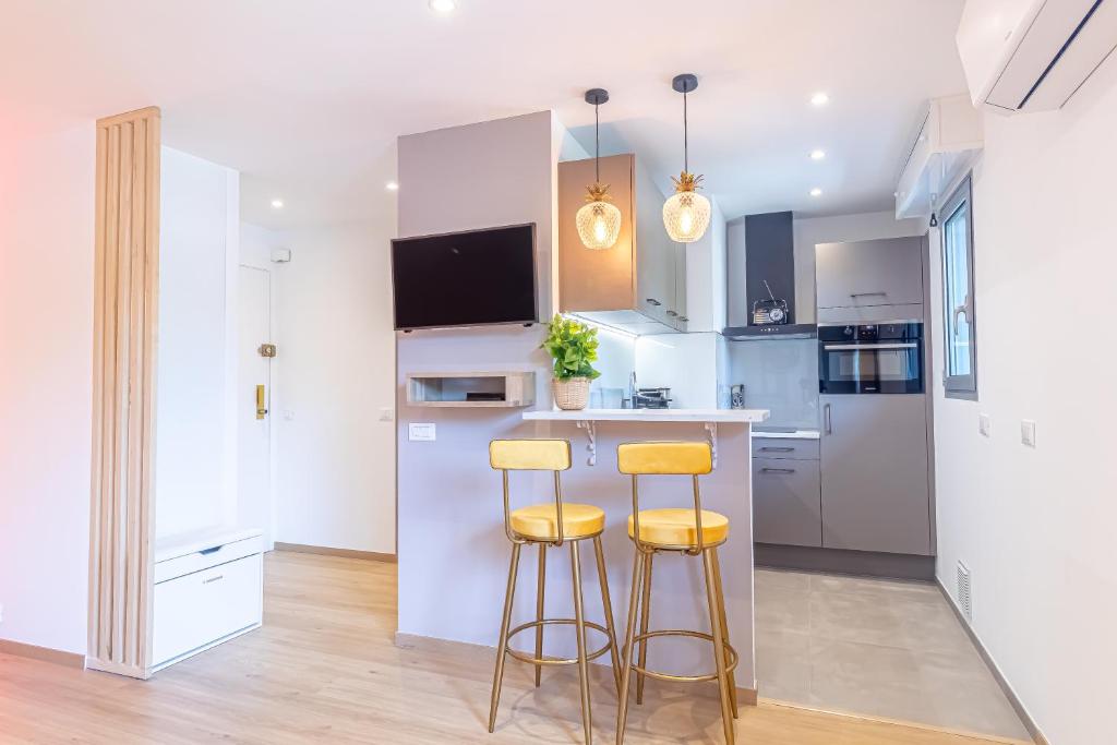 une cuisine avec des armoires blanches et des tabourets de bar dans l'établissement Le 182 promenade du soleil, à Menton