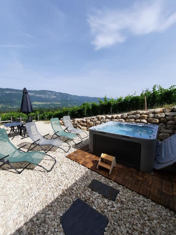 eine Terrasse mit einem Whirlpool, Stühlen und einem Tisch in der Unterkunft La Char'Vigne in Anglefort