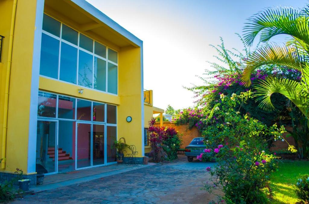a yellow building with a palm tree in front of it at Room in Villa - Comfortable and welcoming Suite with terrace overlooking the lake in Antananarivo
