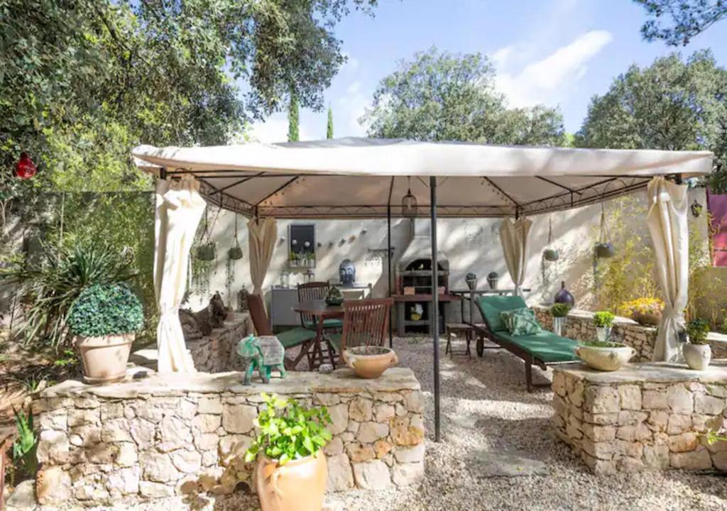 um gazebo num quintal com uma parede de pedra em Les Jardins d'Holi proche Uzès em Garrigues-et-Sainte-Eulalie