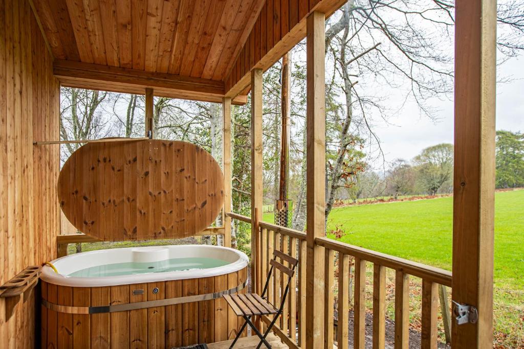 une baignoire jacuzzi sur la terrasse couverte d'une maison dans l'établissement Breckland Lodge 4 with Hot Tub, à Belladrum