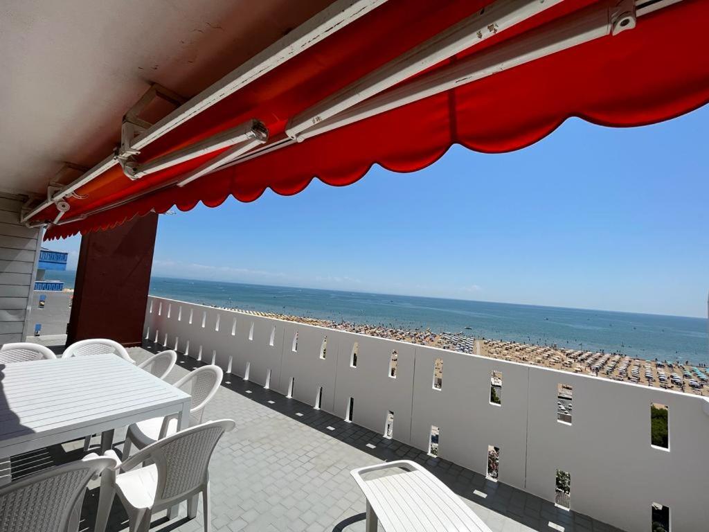 une terrasse avec une table et des chaises et la plage dans l'établissement Residence Luna, à Lignano Sabbiadoro