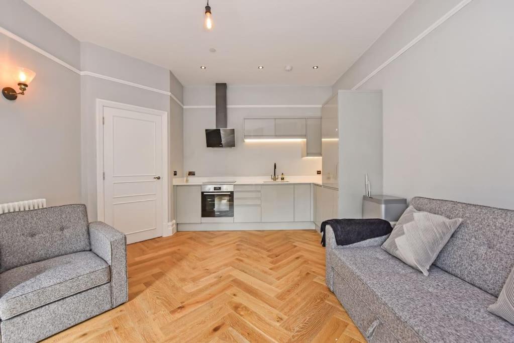a living room with two couches and a kitchen at Luxury apartment stay in Cardiff