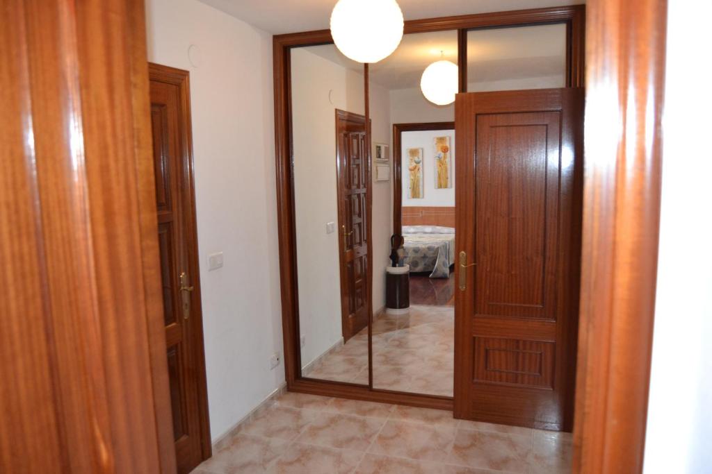 a hallway with a mirror and wooden doors at Inmoinsuas Plaza de Galicia 32 in Sarria