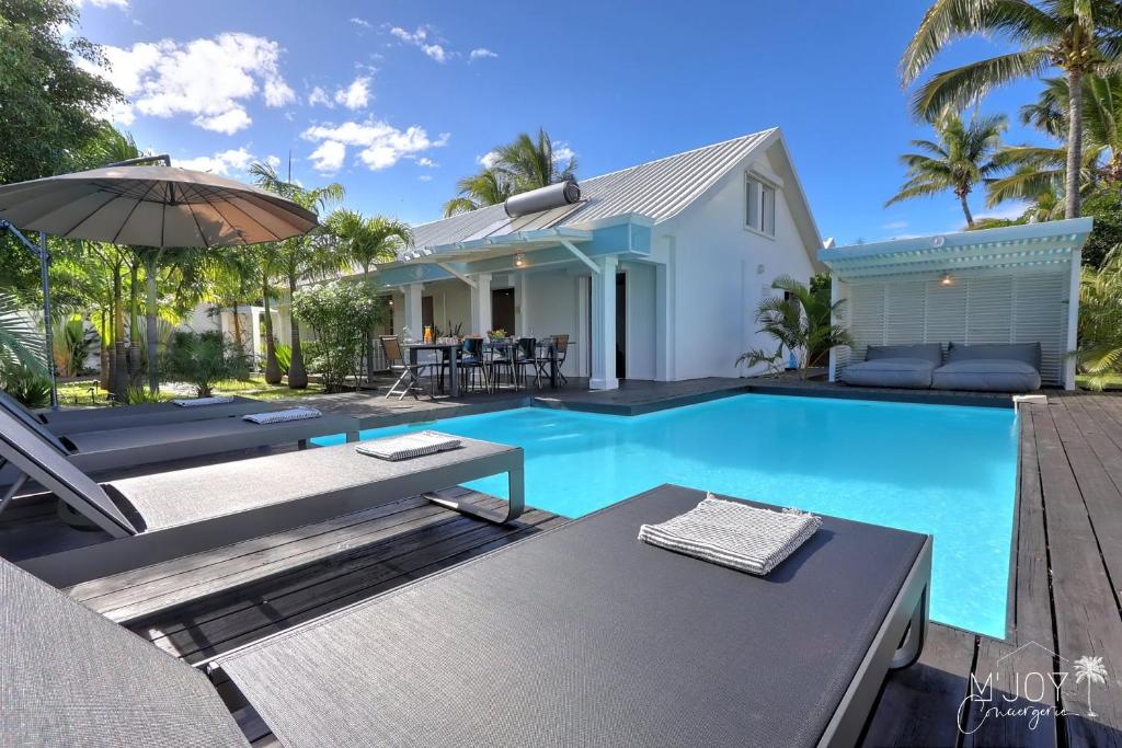 a swimming pool with an umbrella and a house at VILLA KELOHA - Luxueuse villa créole in Étang-Salé les Bains