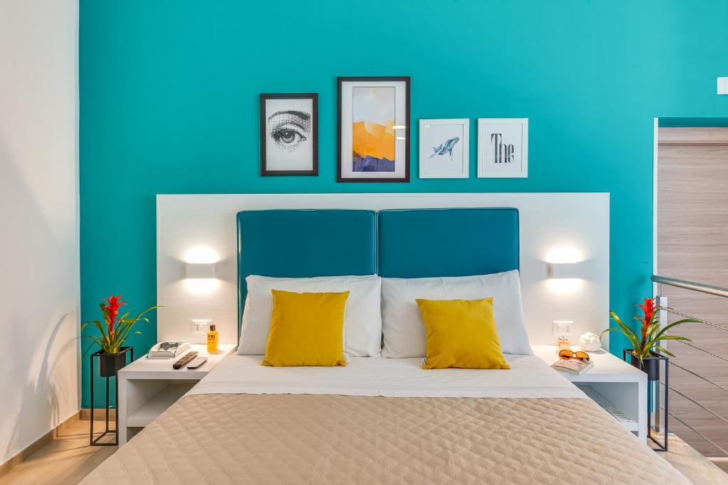 um quarto azul com uma cama grande e almofadas amarelas em Anima Rooms Apartments em Sciacca