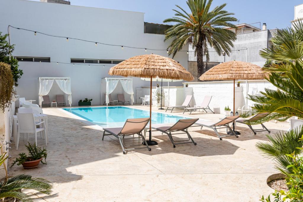 - une piscine avec des chaises et des parasols à côté d'un bâtiment dans l'établissement La Gemma del Salento, à Racale