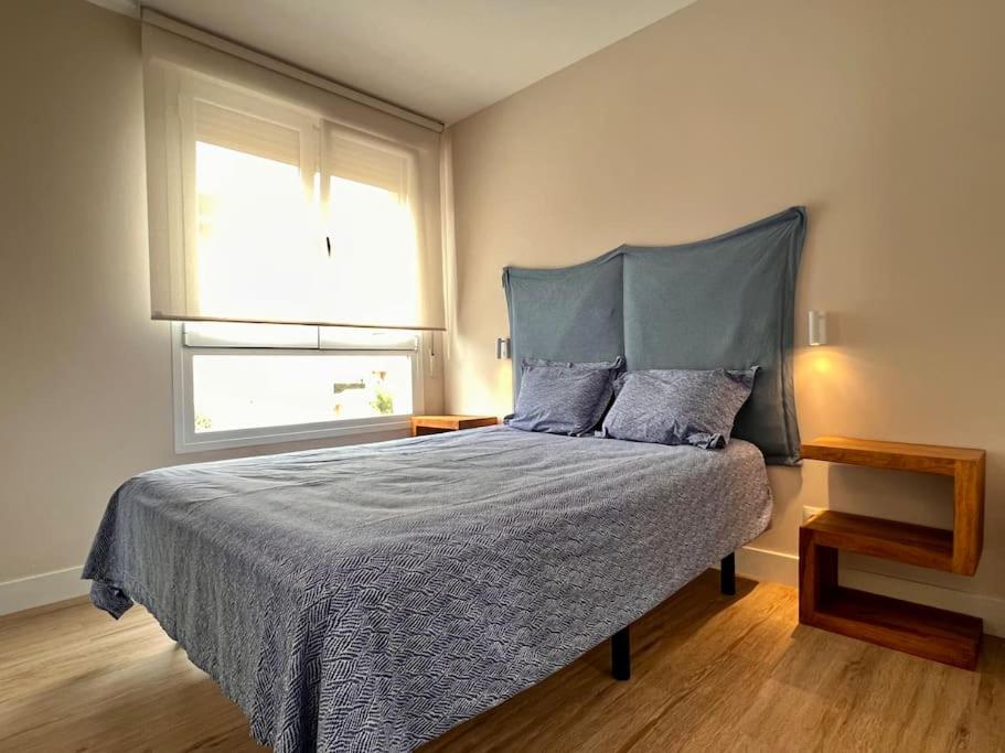 um quarto com uma cama com uma cabeceira azul e uma janela em Acogedor apartamento en Somo em Somo