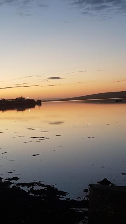 una puesta de sol sobre un cuerpo de agua en 1 Taits Flat en Orkney